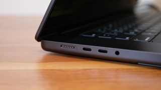 A close up of a black laptop's side connectivity ports on a wooden desk.