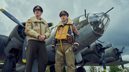 Callum Turner and Austin Butler in Masters of the Air, standng by a plane wearing pilots' uniform