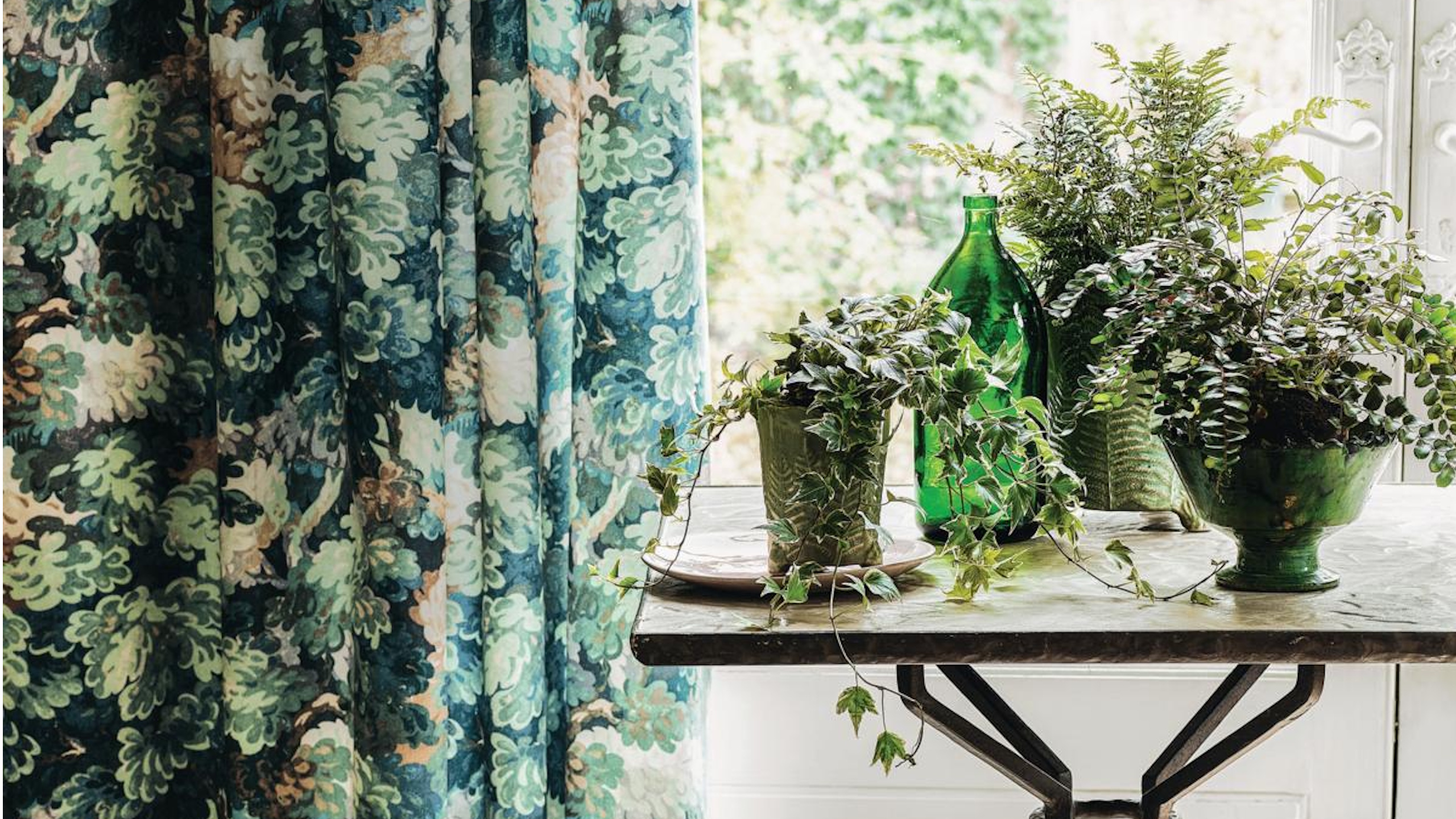 Houseplants on table next to patterned curtain