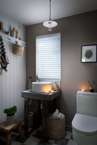 A small powder room with a venetian blind in the window