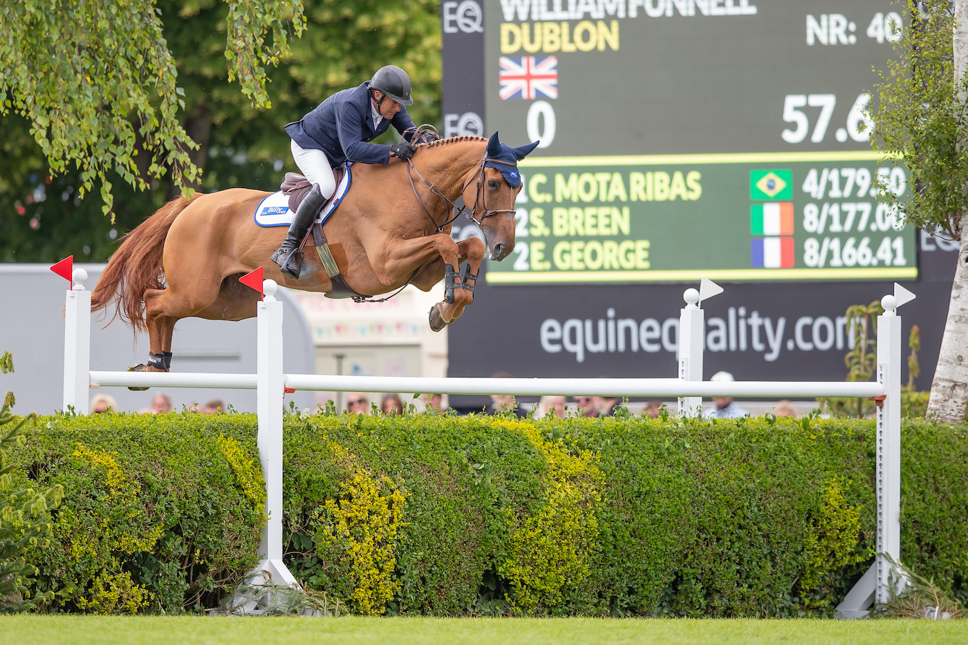 William Funnell clears the private hedge on the Hickstead Derby course riding his chestnut horse Dublon