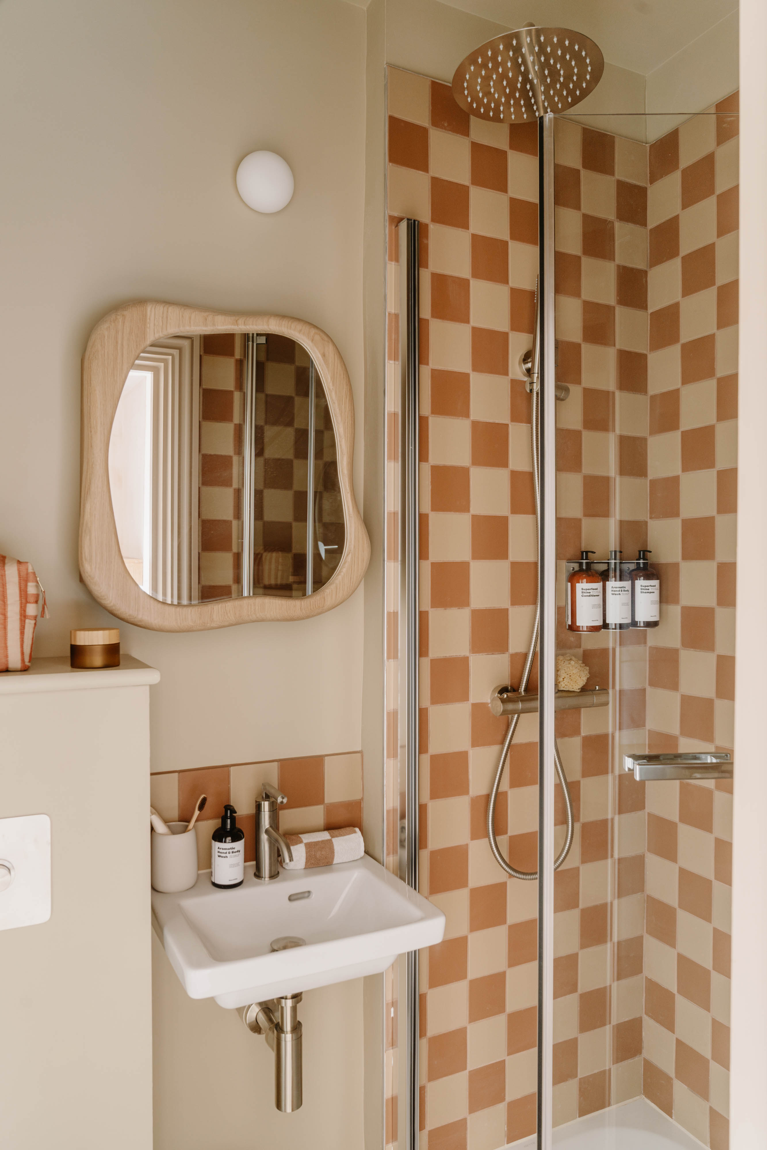 A neutrally tinted hotel with argilla-toned walls, sculptural furnishings, wooden surfaces, and curated art and tilework.