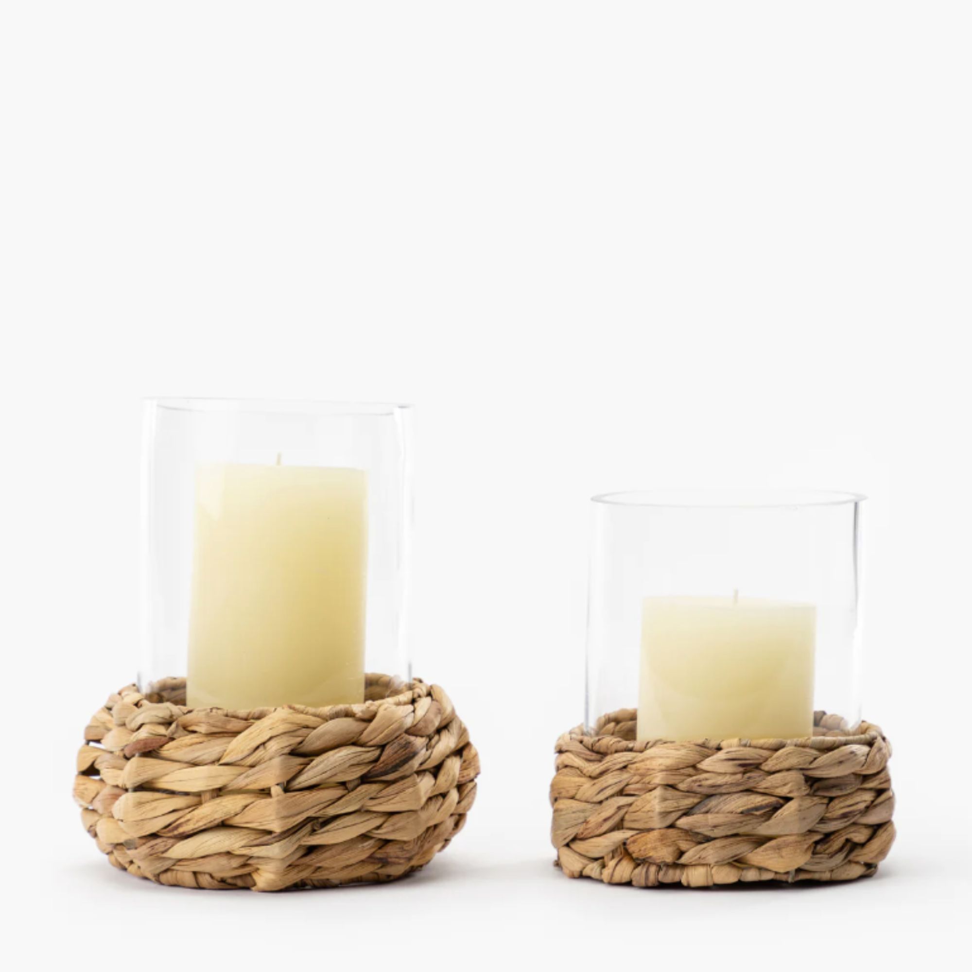 two glass hurricane lanterns with woven bases