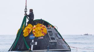 A man stands on a metal dome in the middle of a sea.