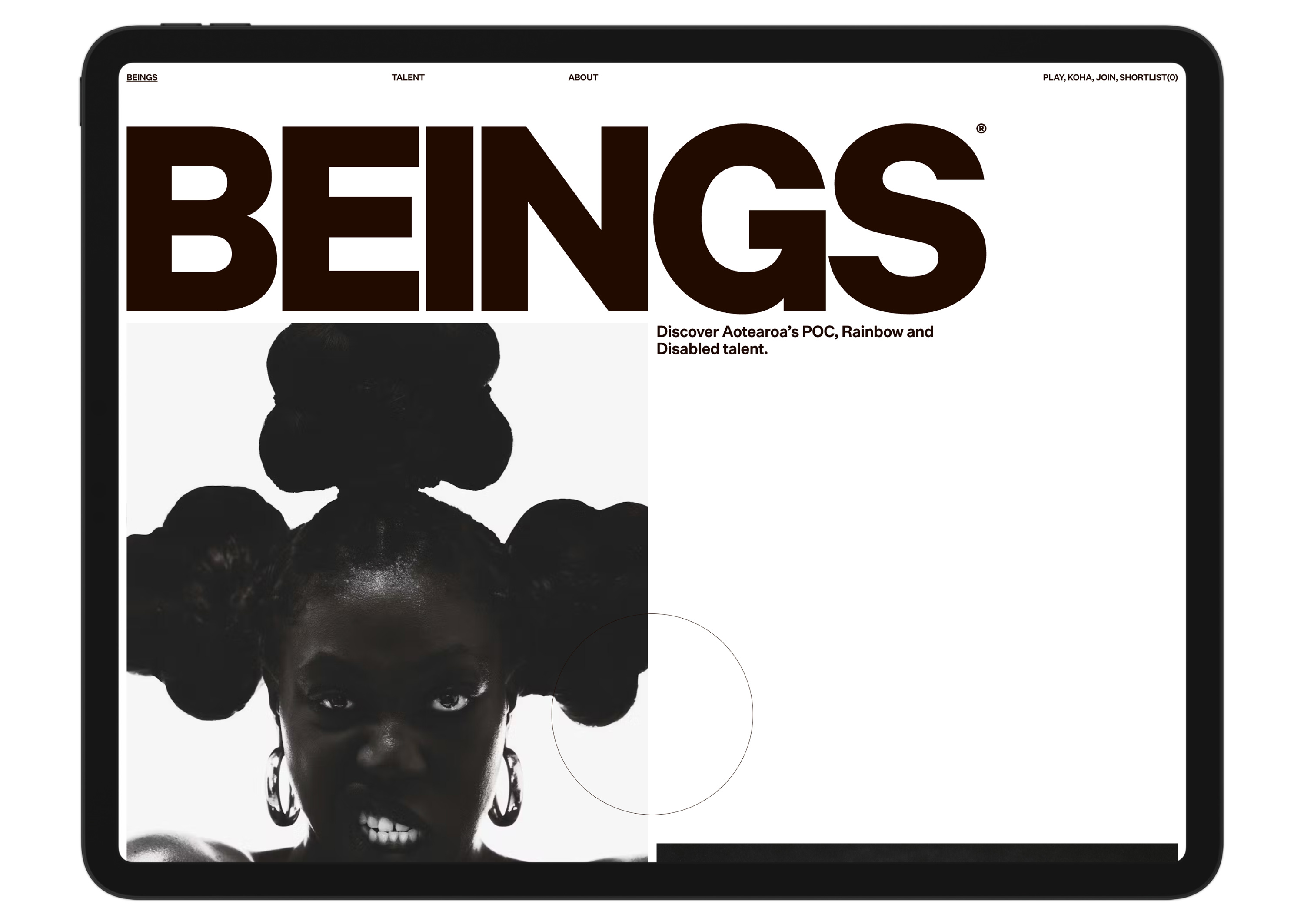 A digital tablet displays a website landing page with the large word "BEINGS" and a high-contrast, artistic black-and-white photo of a person with an elaborate hairstyle.
