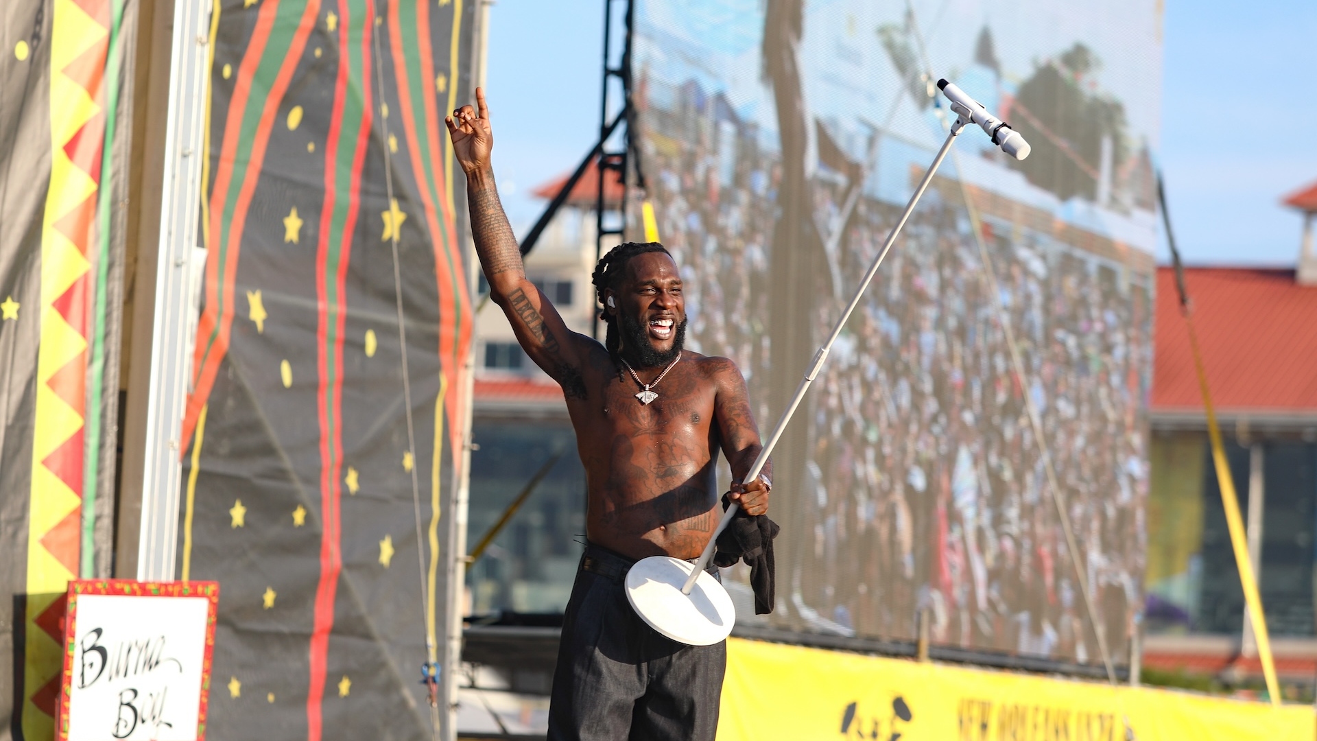 Burna Boy performing on stage holding his mic stand in the air 