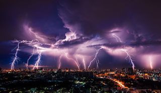 lightning bolts over a city with a purple sky