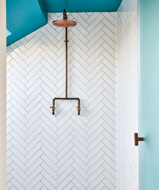 Fun small bathroom with blue sloped ceiling, tonal mint door and white herringbone wall tiles
