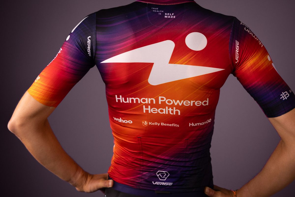 Human Powered Health riders pose in new 2026 team kit, a blend of purple and orange