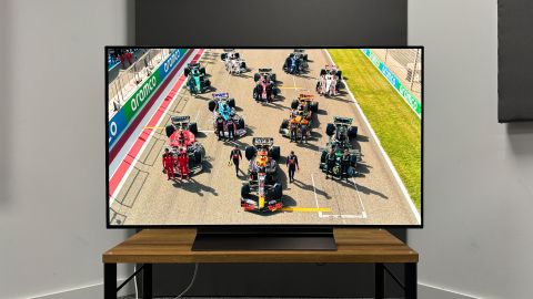 LG C4 (OLED48C4) 48-inch TV on wooden TV bench straight on view with F1 cars on screen