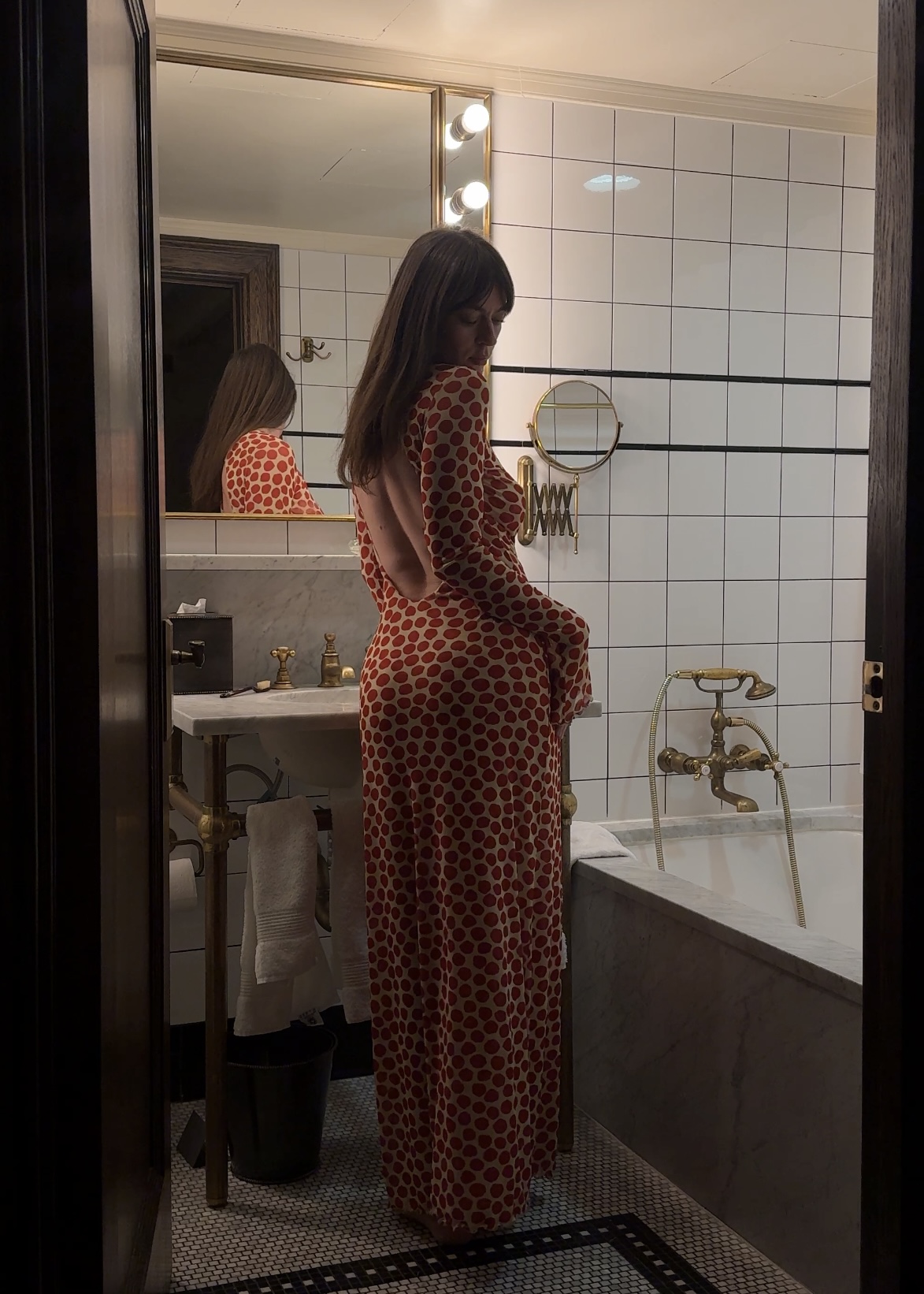 Kathryn Zahorak in bathroom wearing red polka dot backless dress