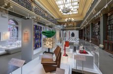 Several furniture designs and objects shown on plinths inside a library of the Victoria & Albert Museum, London