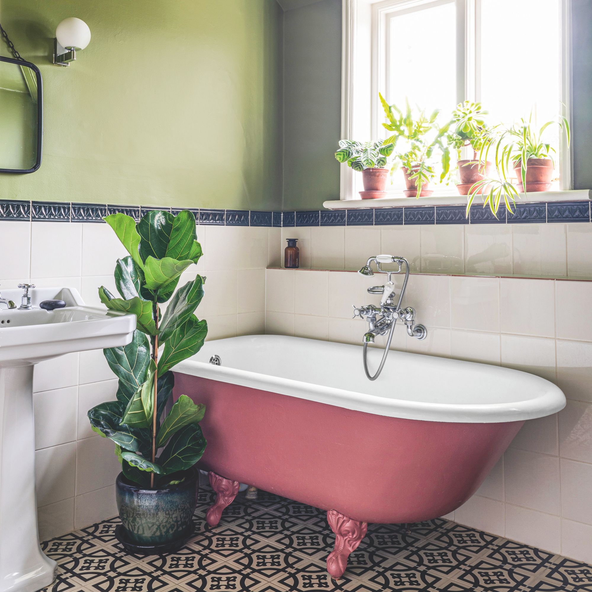 A bathroom with green walls, white tiles and a pink bath, with house plants