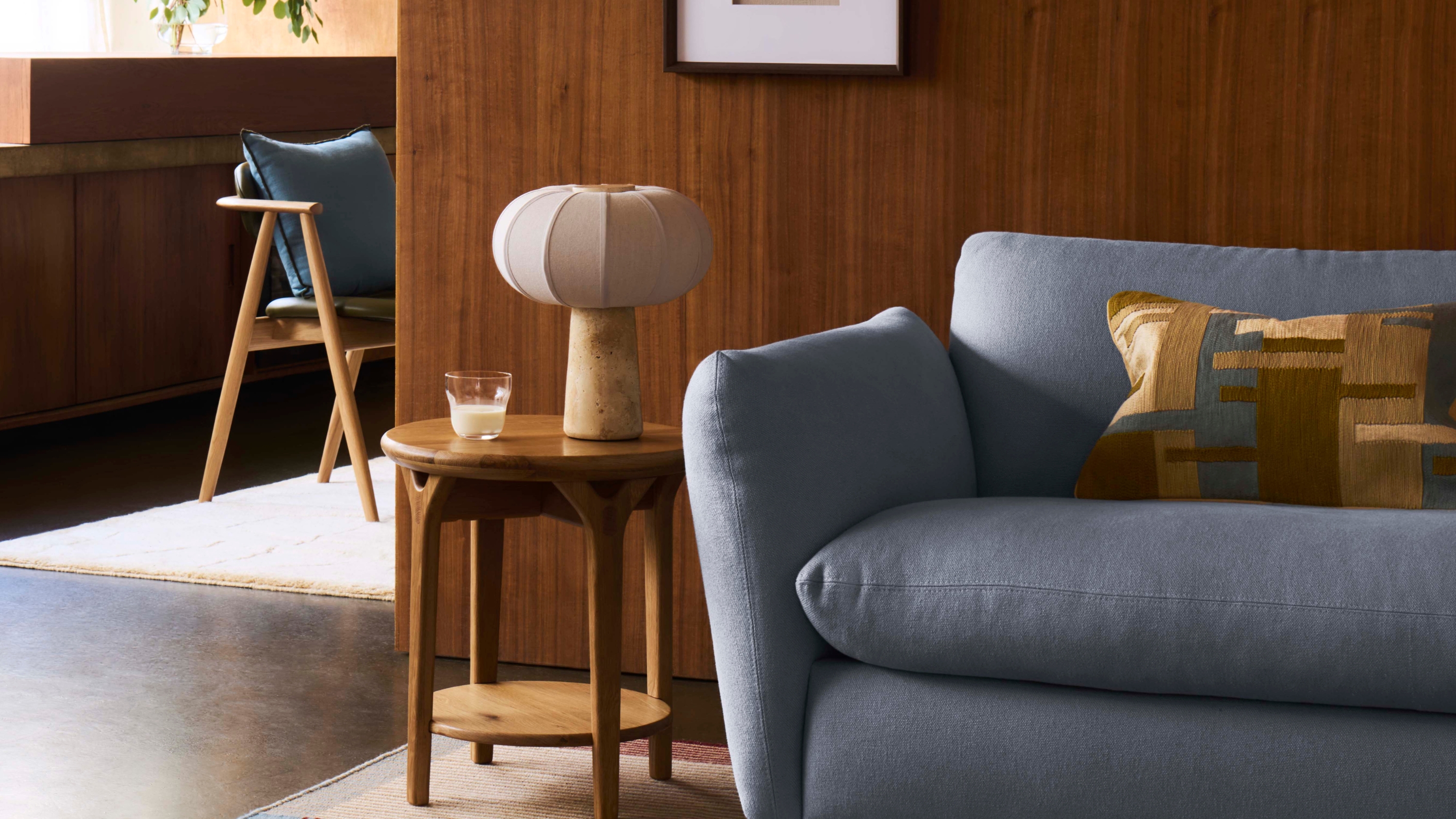 a mid century inspired living room with a light blue sofa and a pumpkin shaped stone table lamp