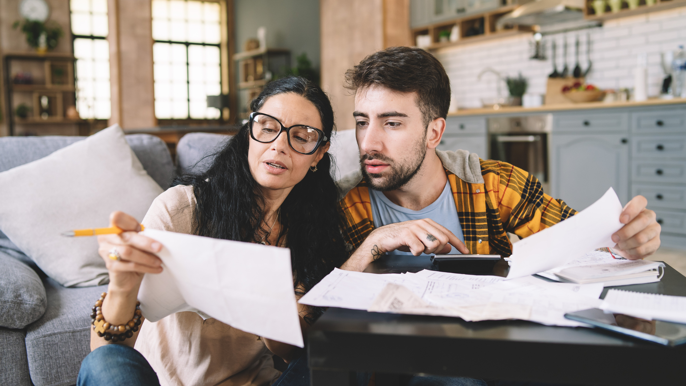 Couple calculating bills at home using calculator