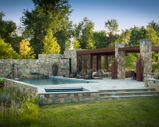 A pool with pool house built from wood and rustic natural stone