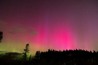 northern lights appears as vibrant pink and green curtains filling the sky.