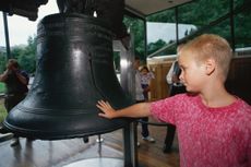 A child reaches out to touch the Liberty Bell.