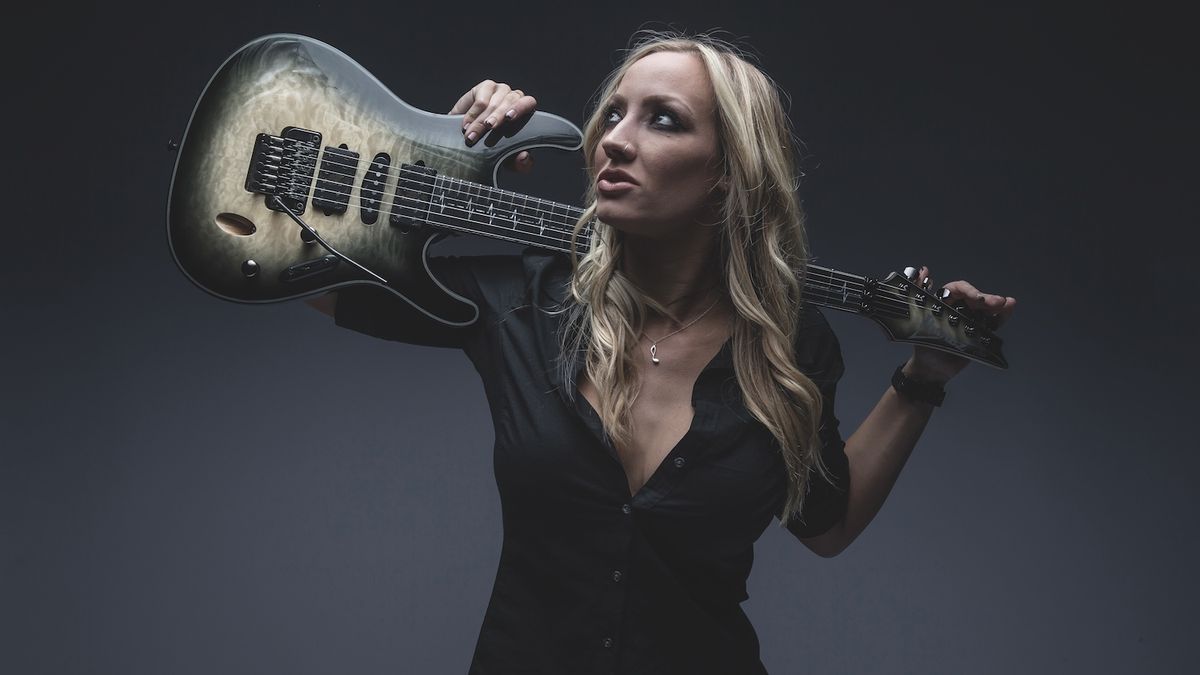 Alice Cooper guitarist Nita Strauss holds her Ibanez guitar over her shoulders