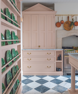pink kitchen cabinet with black and white marble checkerboard flooring and green ceramic portuguese plates