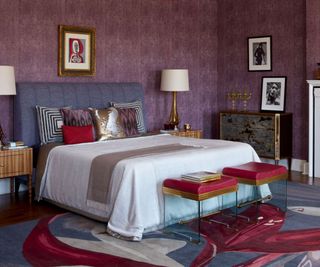 double bedroom with grey upholstered headboard with white bedspread and purple wallpaper and statement rug