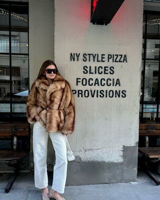 fashion influencer in faux fur coat and white trousers