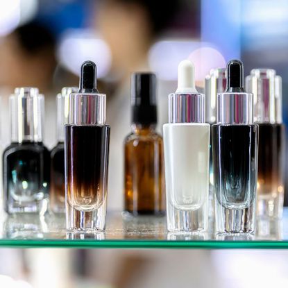 unidentifiable skincare bottles on a glass shelf
