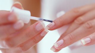 Image of woman painting nails with sheer pink nail polish