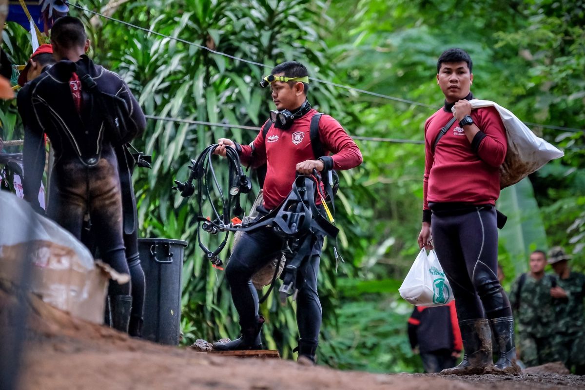 Thai marine police walk out of Tham Luang caves on July 3, 2018, wearing their scuba gear as they continue the rescue operation of 12 boys and their soccer coach who have been stranded for over a week after monsoon rains blocked the main entrance in Chian