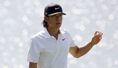Anthony Kim waves to the crowd whilst holding a golf ball