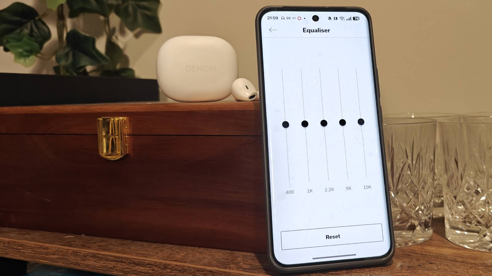 The Denon AH-C500W next to a phone with an equalizer open.