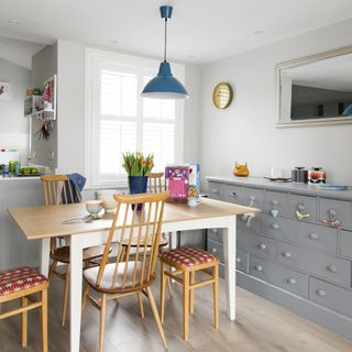 dining area with white wall grey drawers cabinet dinning table with chair and wooden flooring