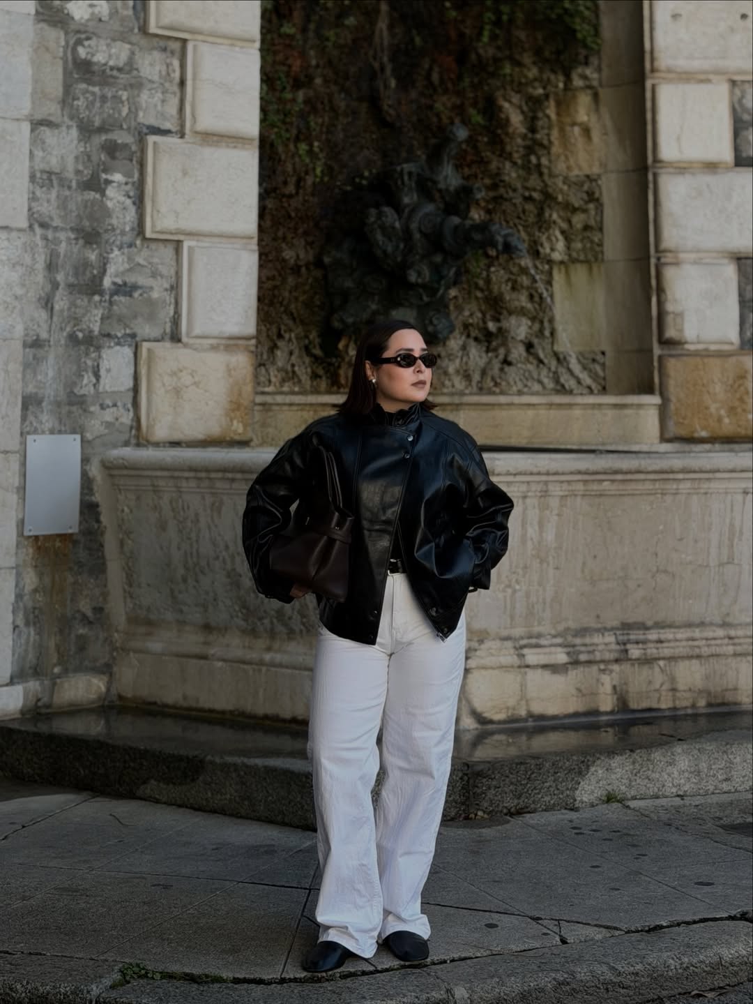 Influencer Indira C wearing a leather jacket and white jeans.