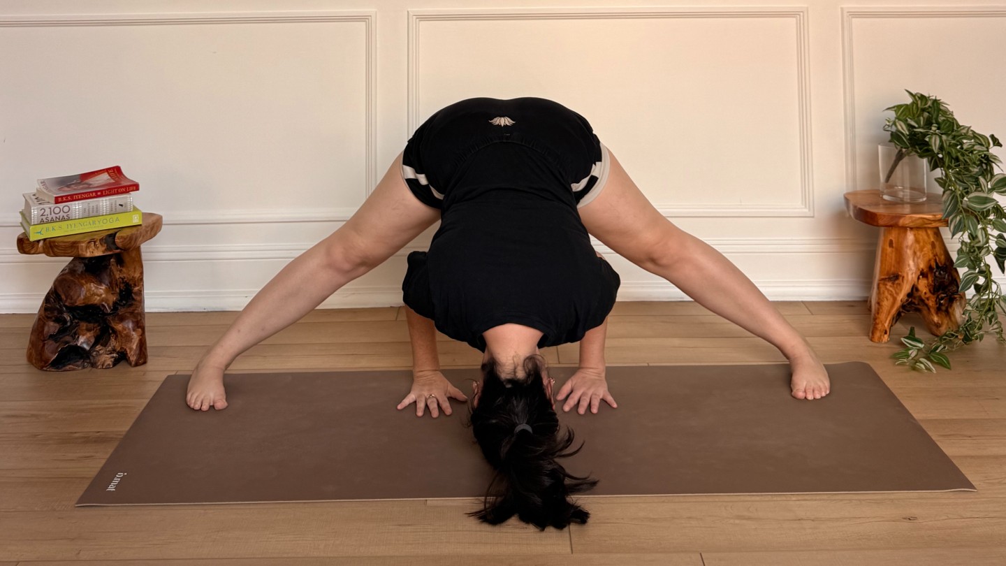 Purdon showing wide legged forward fold on yoga mat
