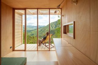 tiny house with yellow deck chair on a viewing platform in the italian mountains