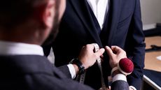 Over-the-shoulder view of a tailor fitting a suit on a man.