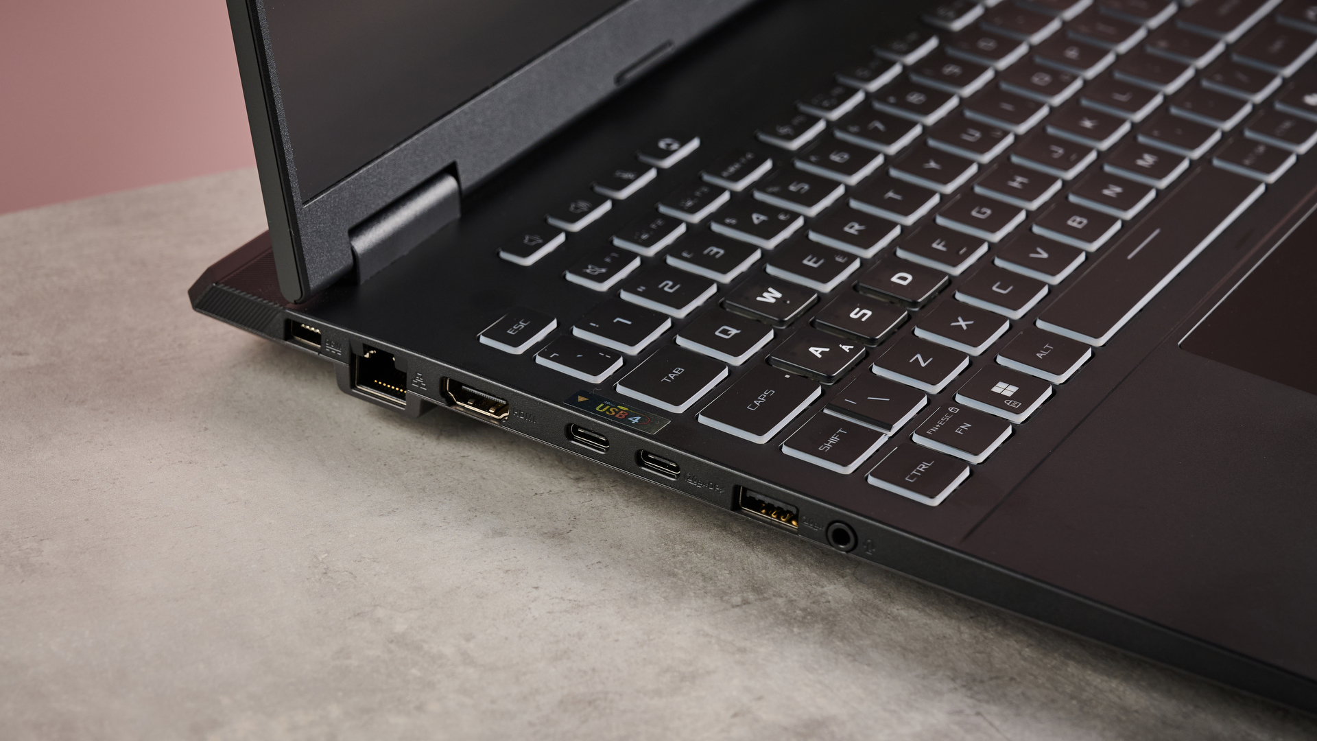 Close-up of left side ports on ASUS TUF Gaming A16 (2025), open on desk with pink background