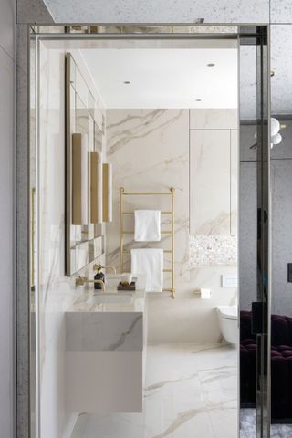 Bathroom with marble effect porcelain floor and wall tile, vanity with mirrors above and towel rail