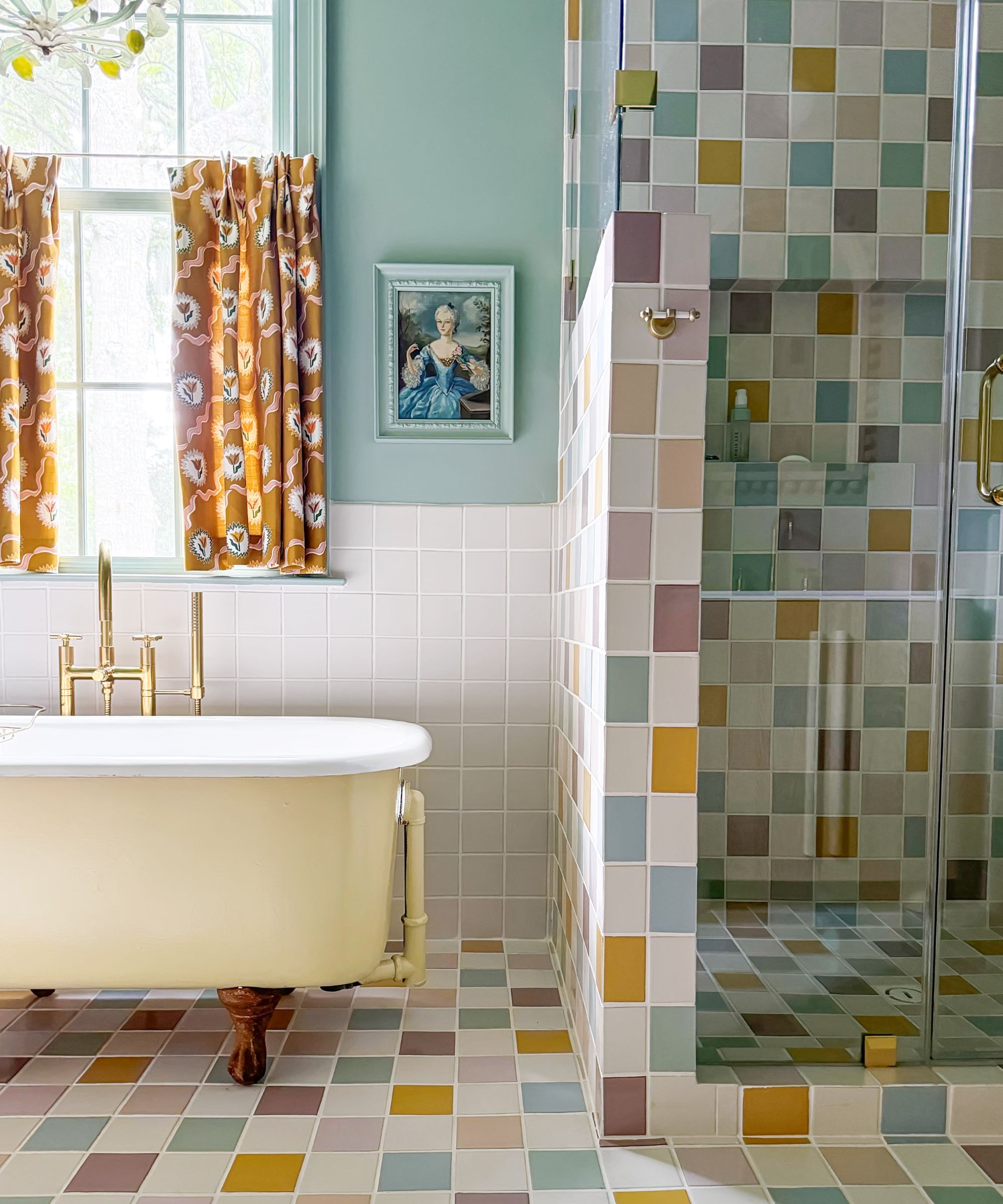 A bathroom with colorful square tiles on the walls and floors, a freestanding butter yellow bathtub, and blue painted walls