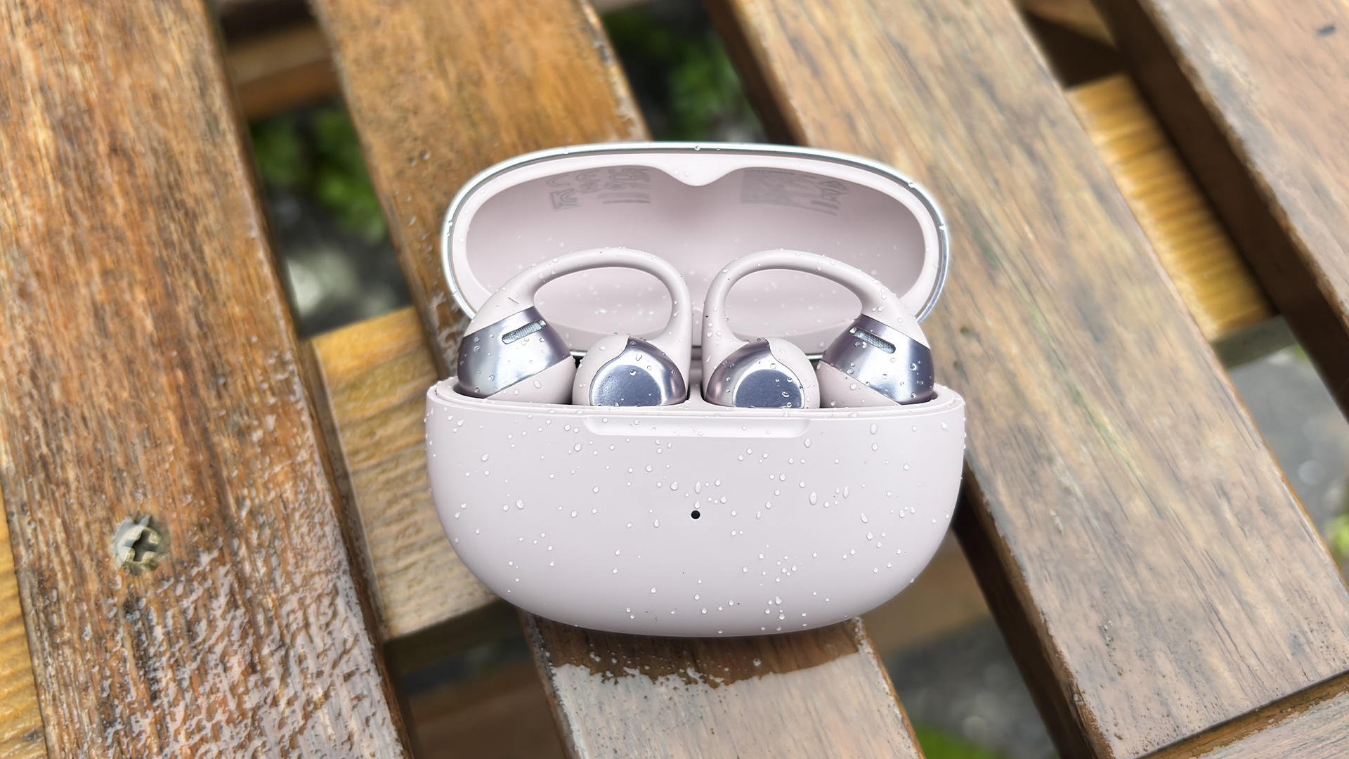 Shokz OpenDots One open earbuds in open case on wooden garden chair