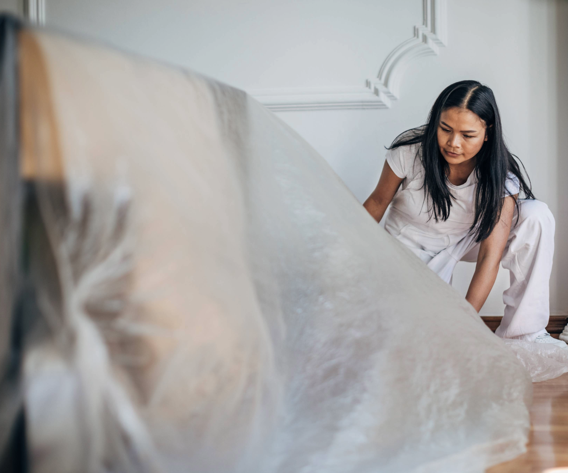 Woman placing a plastic sheet over furniture