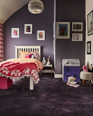 eggplant kids bedroom, artwork on walls, dolls house, white painted bed with orange and dark pink bedding, eggplant colored carpet