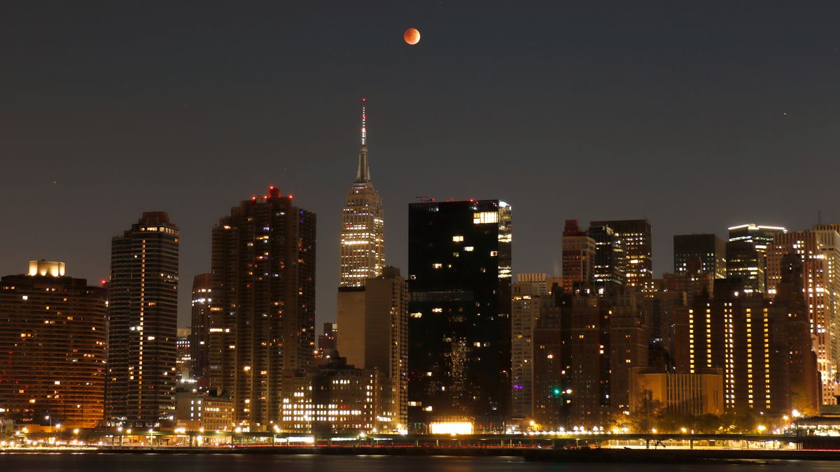 red moon in sky above tall buildings