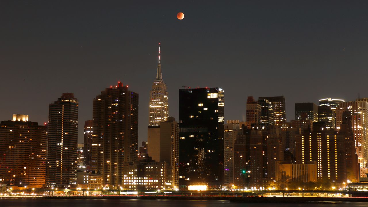 red moon in sky above tall buildings