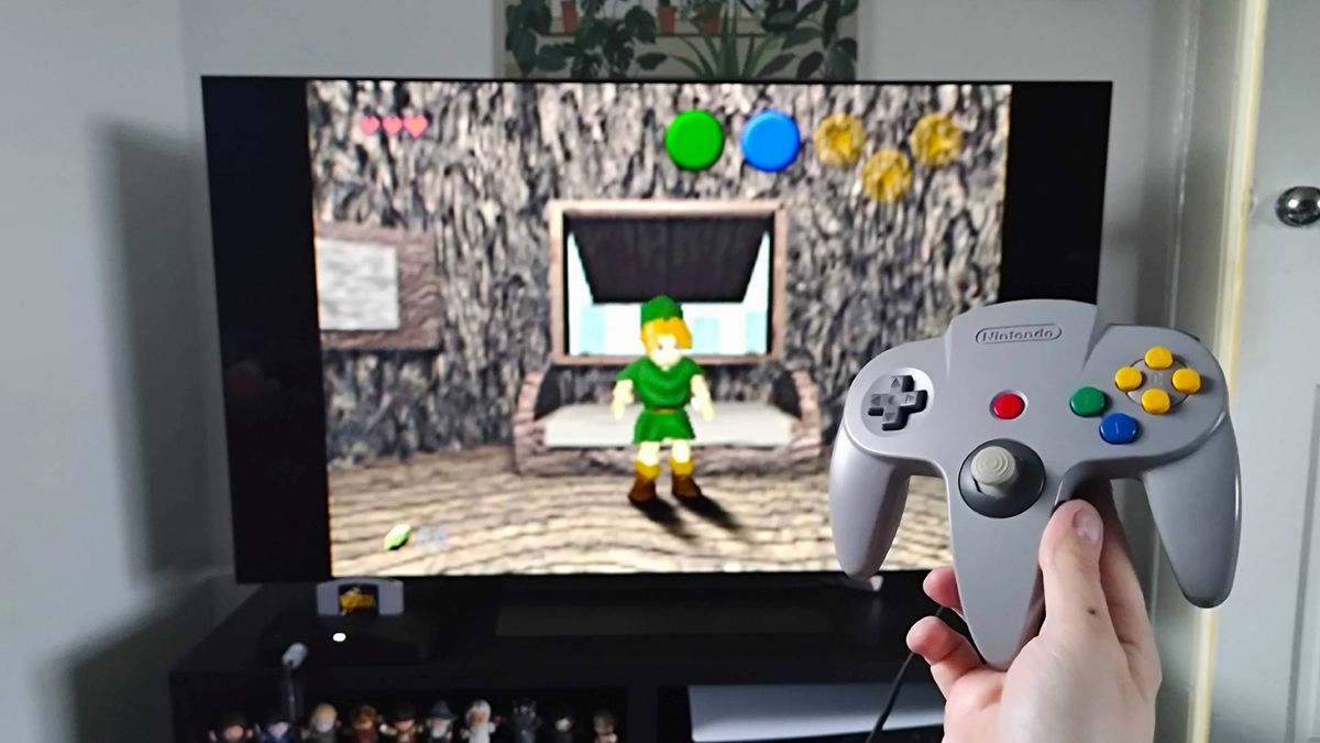 Analogue 3D connected to LG OLED C4 TV with hand holding original grey controller and Zelda: Ocarina of time gameplay in backdrop.