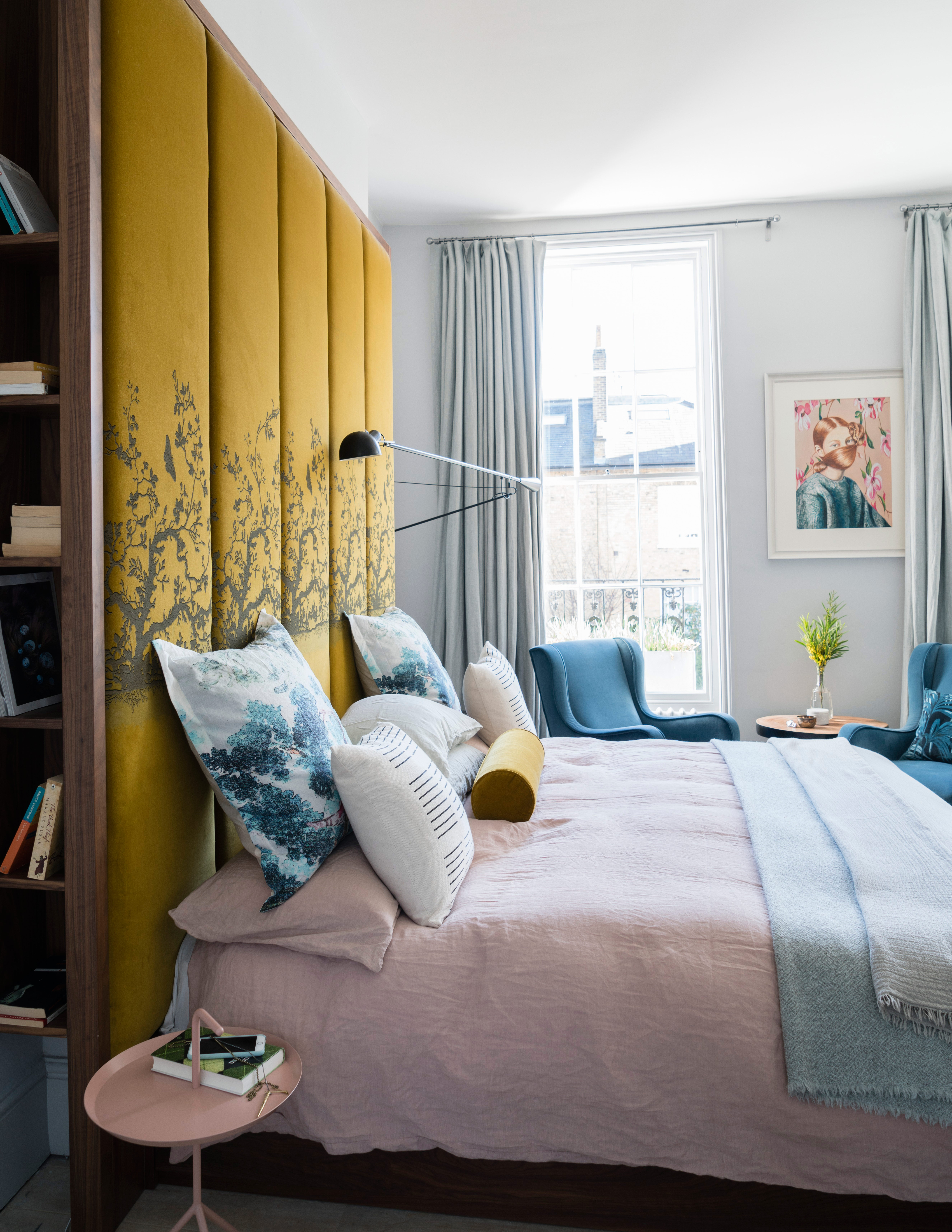 Pink yellow and blue bedroom with large velvet headboard