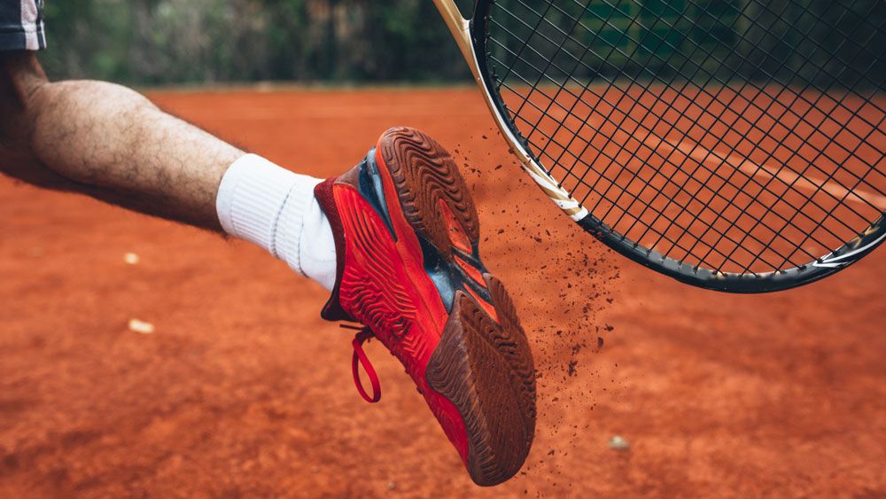 Close-up of sole of tennis shoe next to tennis racket