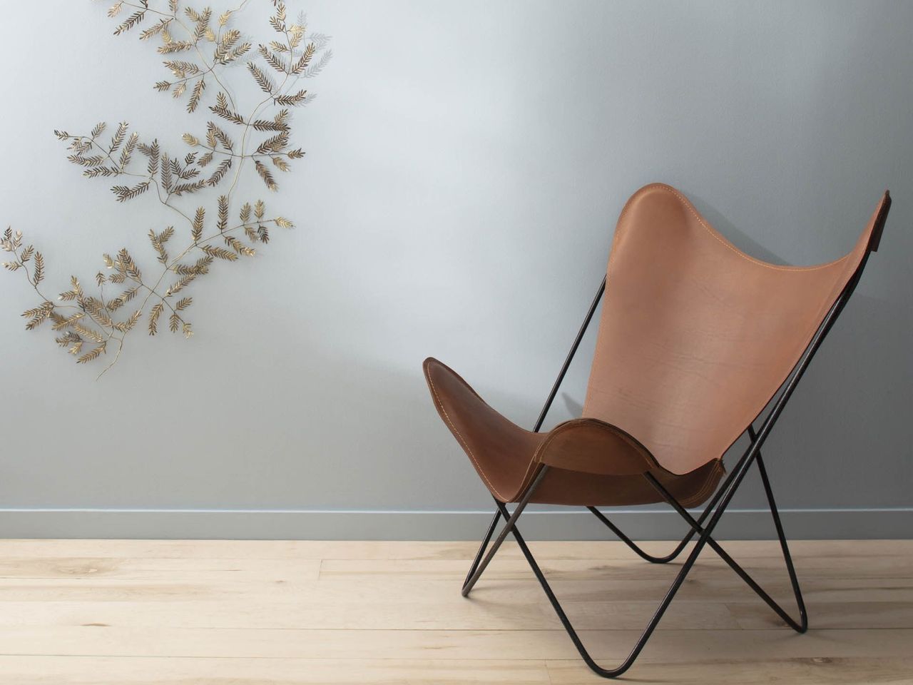 A room with wood flooring, pale blue walls, and a leather accent chair