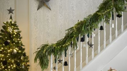 A decorated Christmas tree with presents at the bottom of a staircase