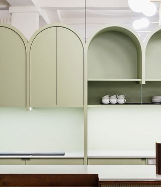 Close up view of the arched pastel green units with shelving at Yorck Kino Passage cinema. There are white mugs and saucers on the shelves